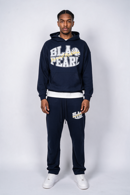 Model wearing the Imperfect By Nature Tracksuit in Navy, front view with BLAQ PEARL varsity graphic on hoodie and joggers